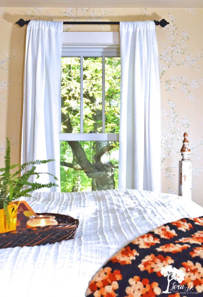 A black and orange vintage afghan brings a bolt of color to this Fall decorated bedroom.