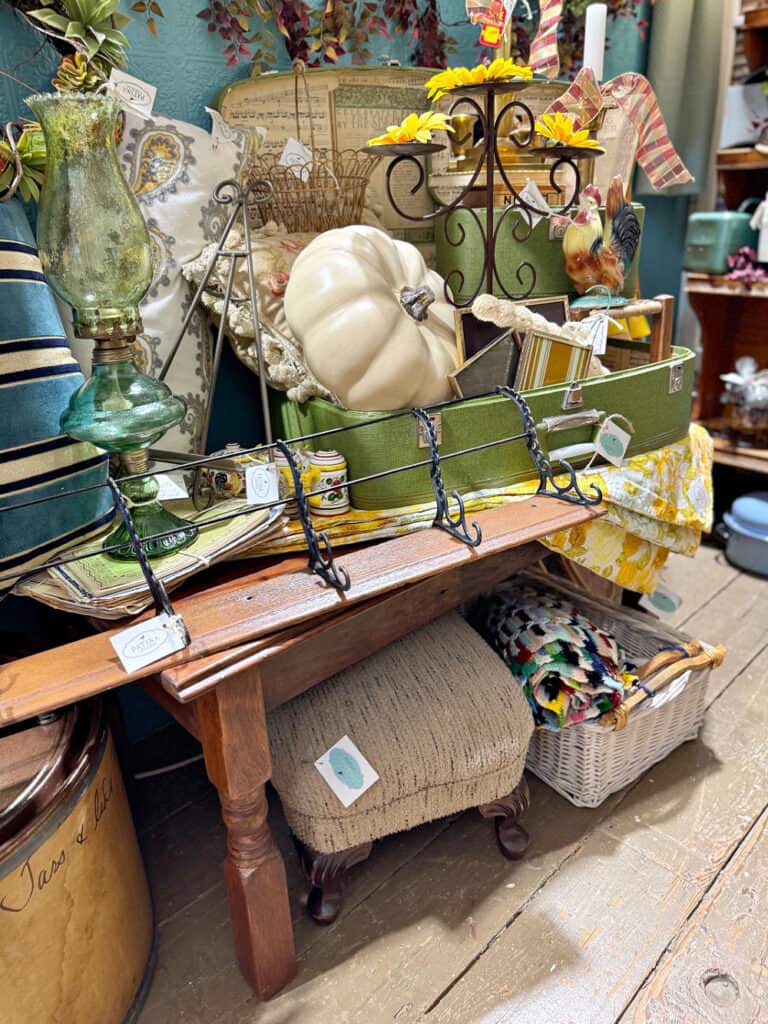 Antique booth display with wood coffee table and green suitcases for fall.