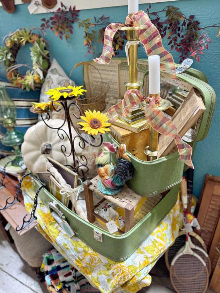 Green vintage suitcases displayed in fall decorated antique booth.
