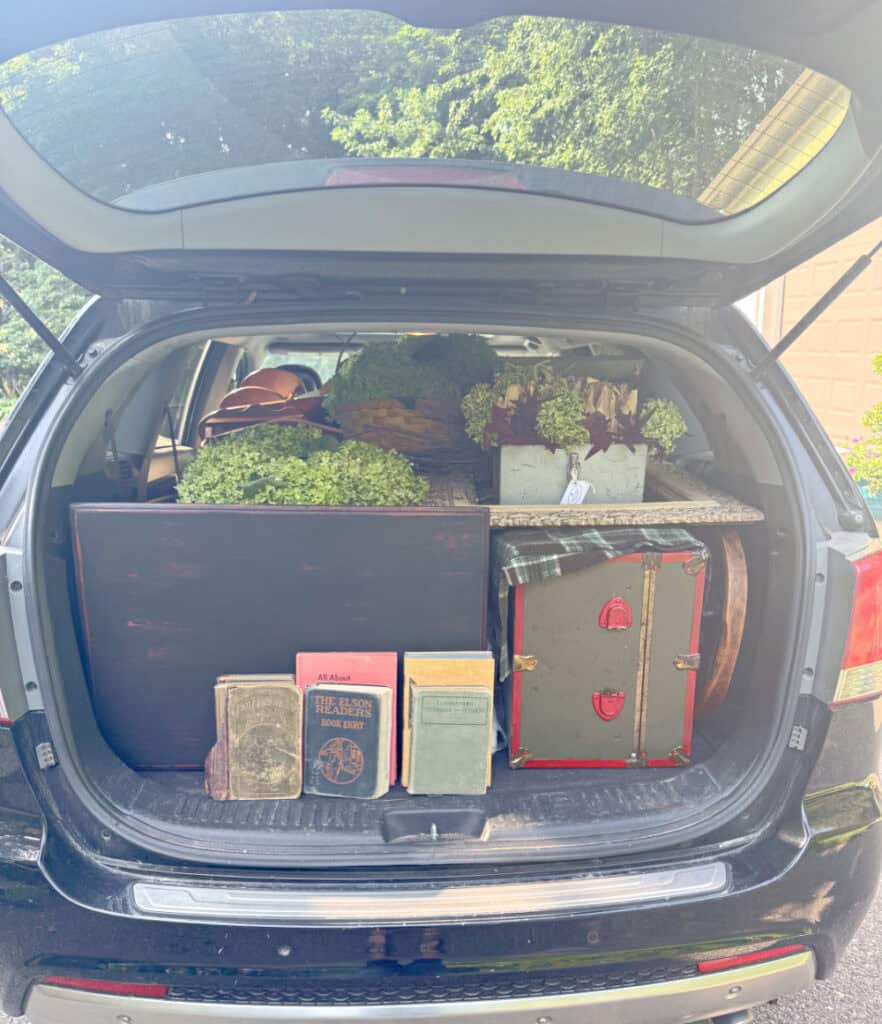 Back hatch of car open full of items to refill vintage booth.