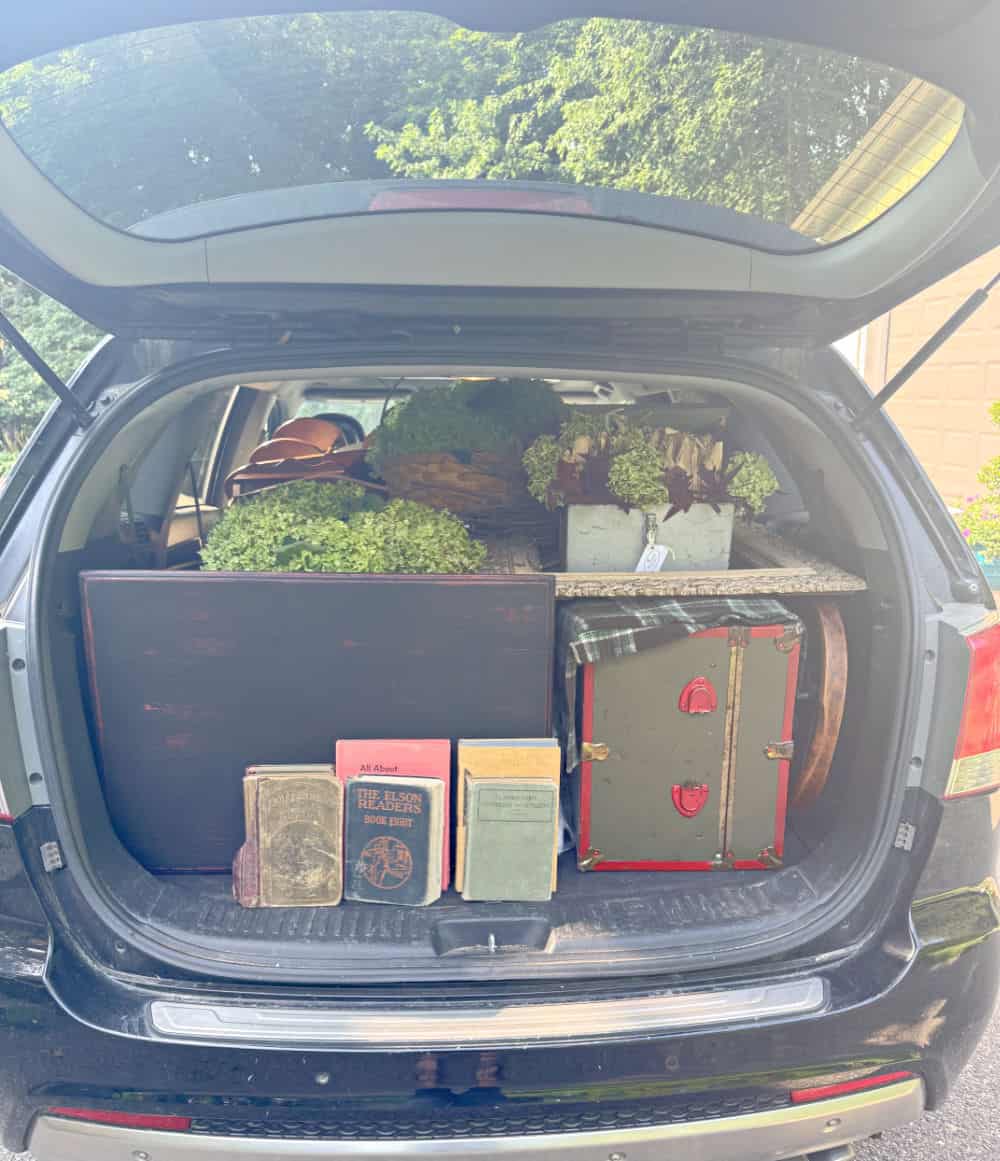 Back hatch of car open full of items to refill vintage booth.