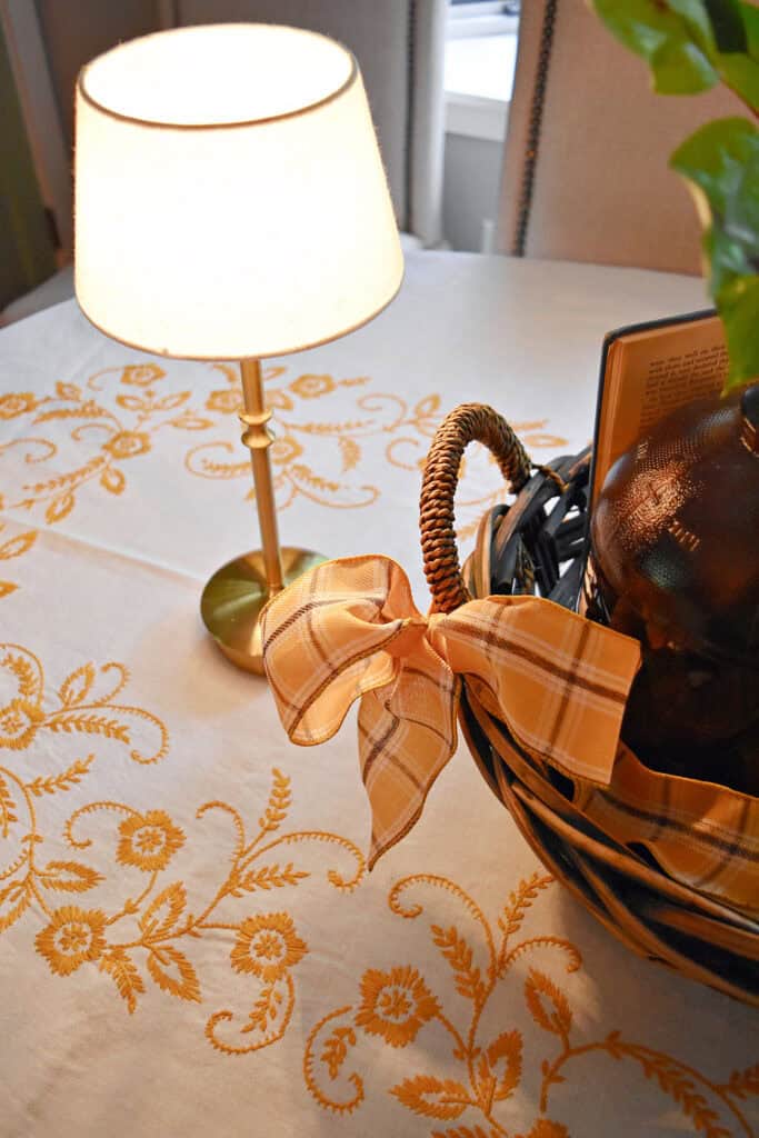 Plaid ribbon bow on basket and embroidered tablecloth.