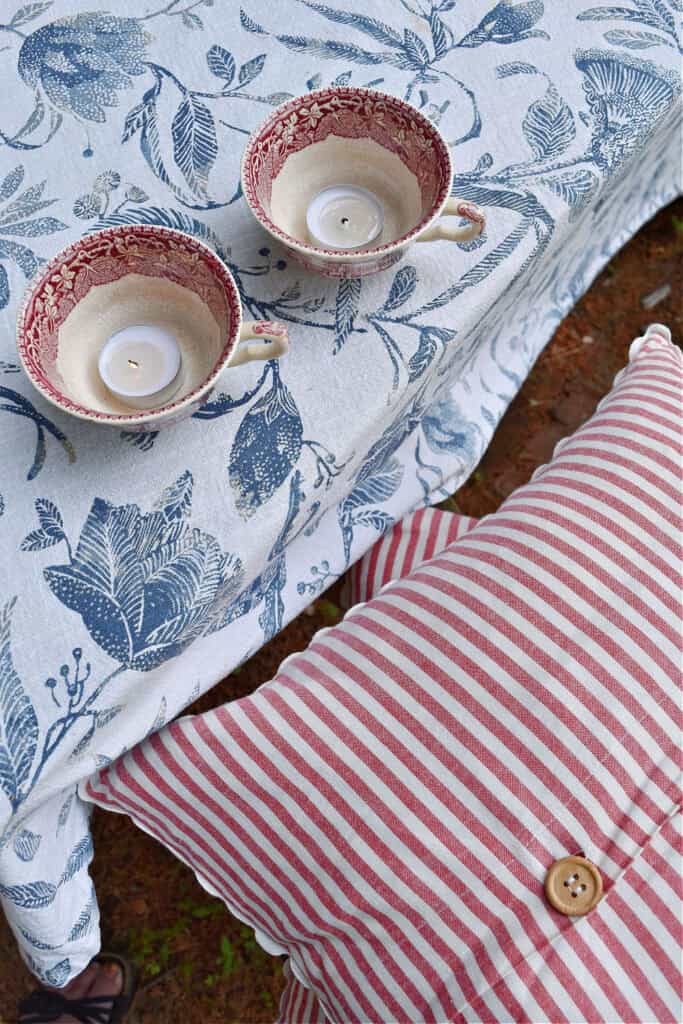 Red and white stripe pillow and blue and white floral tablecloth.