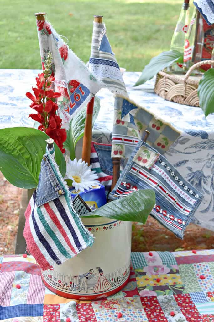 Patriotic colored scrap fabric flags in vintage tin container.