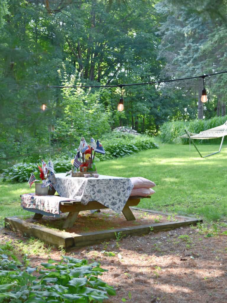 Picnic table with Patriotic centerpiece near woods.