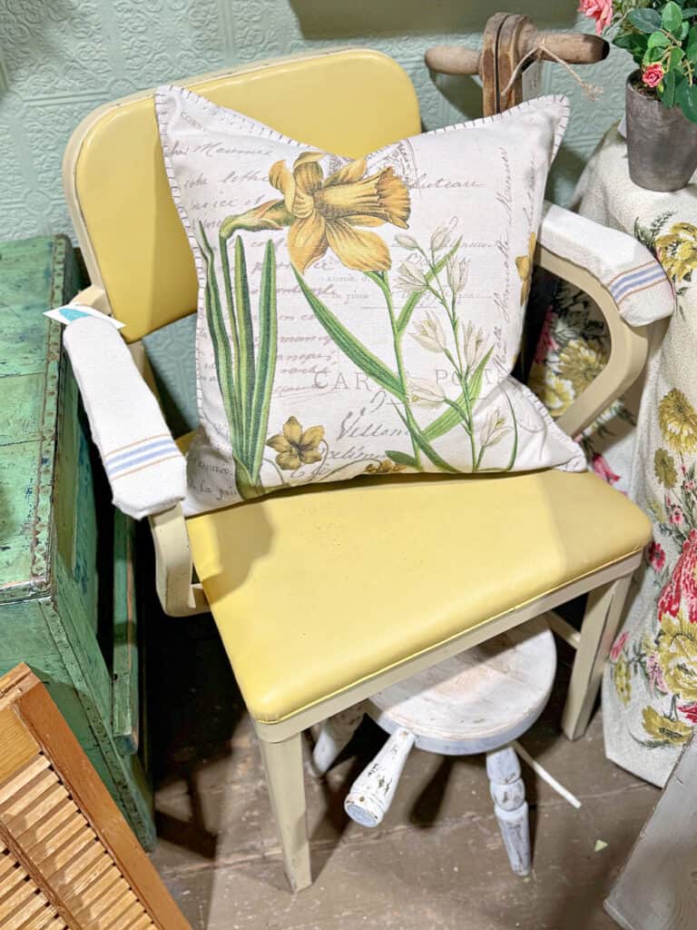 Yellow industrial chair with floral pillow.