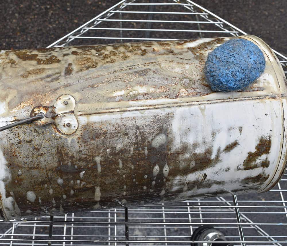 Scrubbing old metal pail with SOS pad.