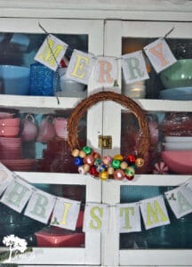 Drape garland or hang a wreath on the front of a glass front cabinet display for another idea.