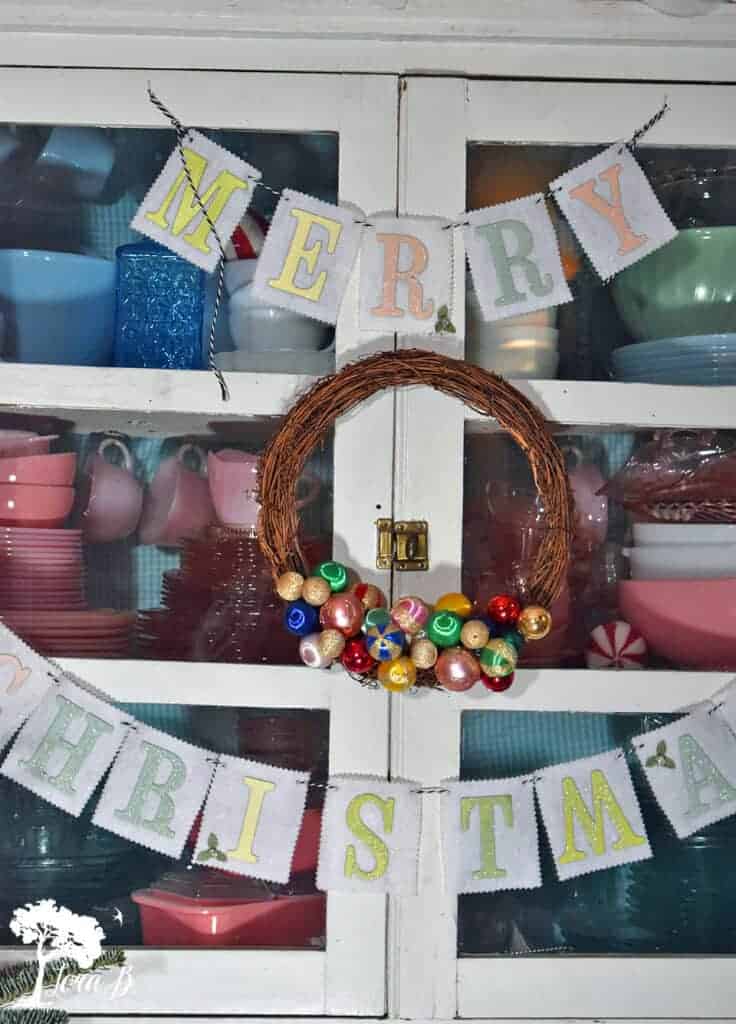 Drape garland or hang a wreath on the front of a glass front cabinet display for another idea.