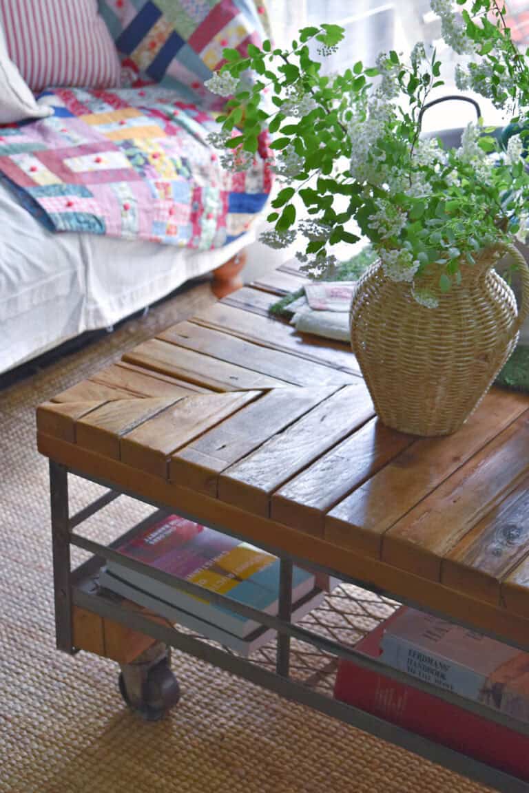 Rustic industrial coffee table, colorful quilt and wicker vase with flowers.