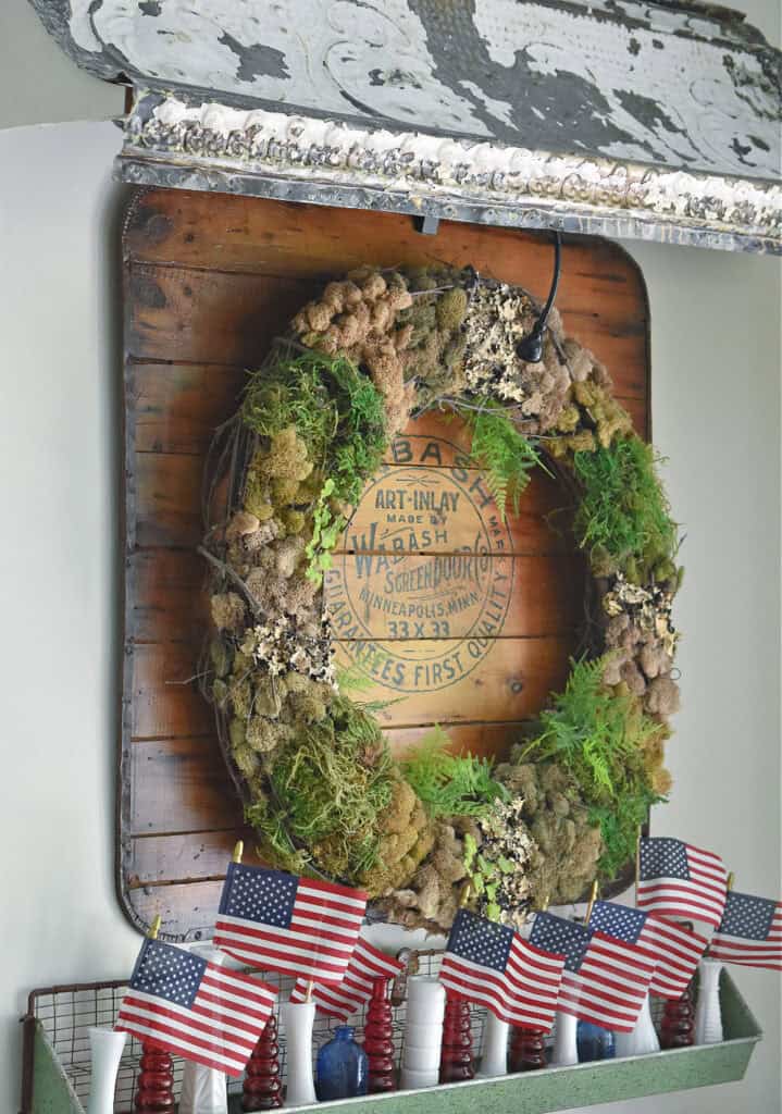 Moss wreath and american flags in milk glass as summer decor.