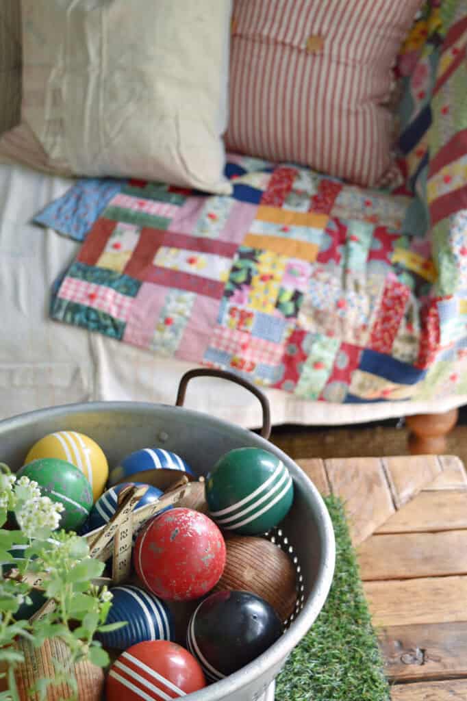 Vintage quilt and croquet balls in colander as summer coffee table decor.
