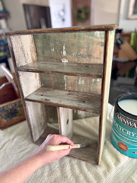 Brushing poly on shabby cabinet.