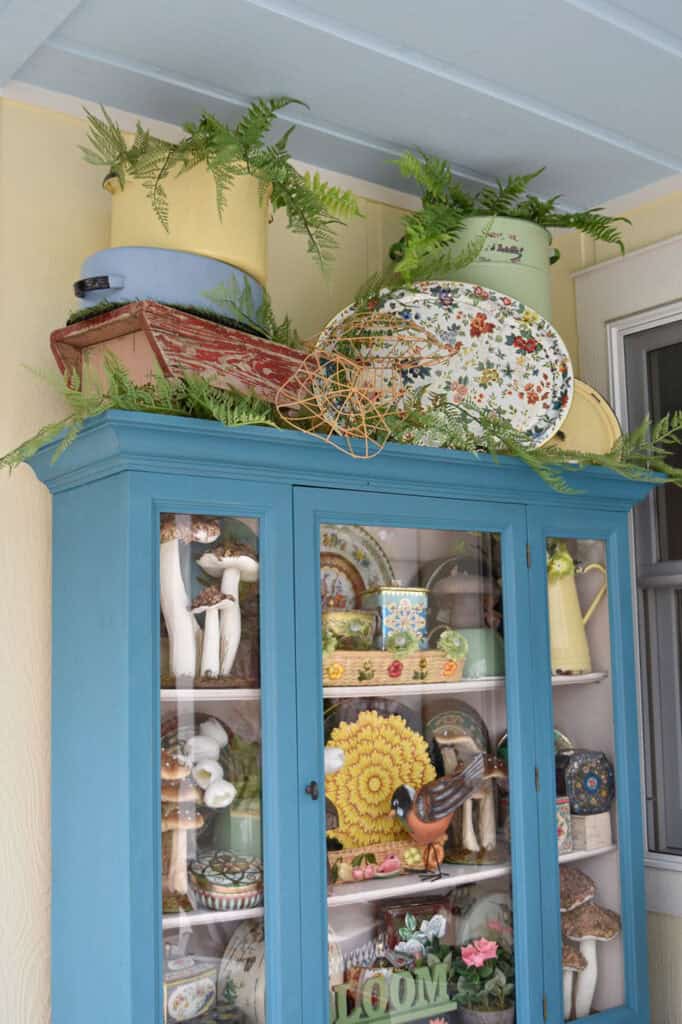 Vintage floral tins display in aqua painted hutch.