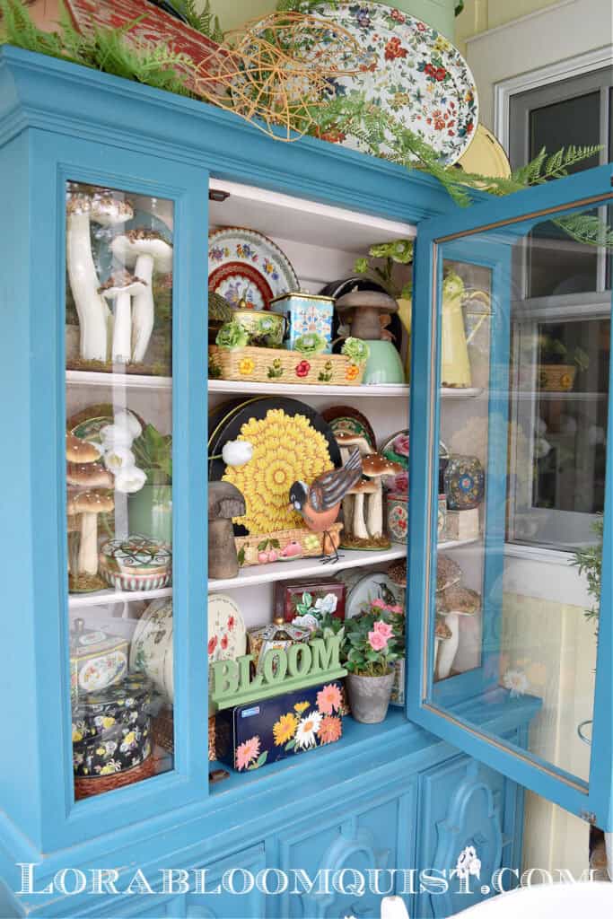 Vintage floral tins display in aqua painted hutch.