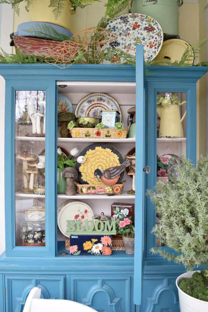 Vintage floral tins display in aqua hutch.