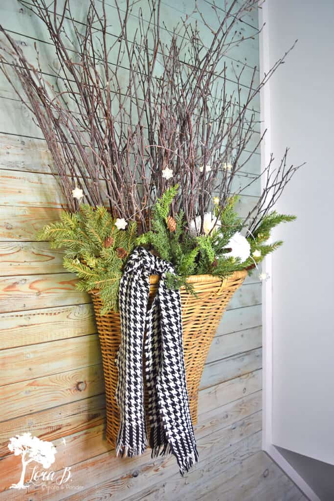 Herringbone scarf decorates a wicker basket with sticks as winter decor.