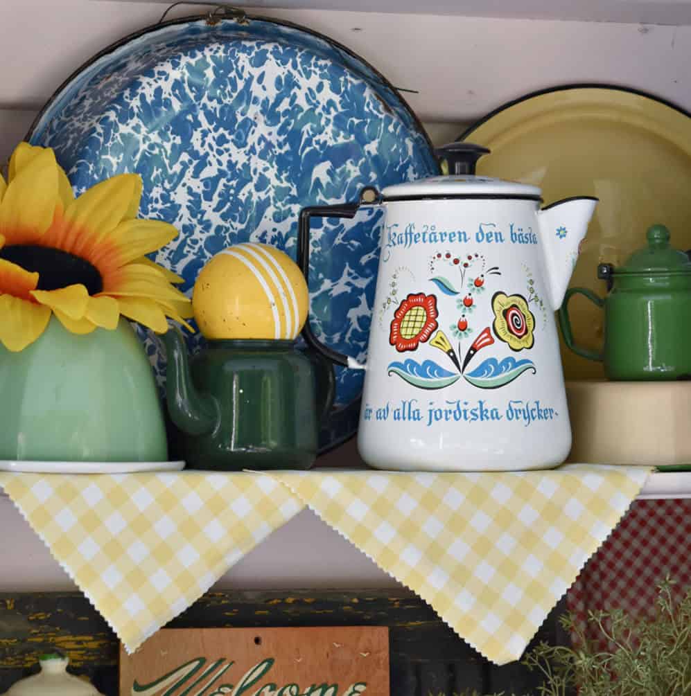 Scandinavian painted enamelware coffee pot displayed on shelf.