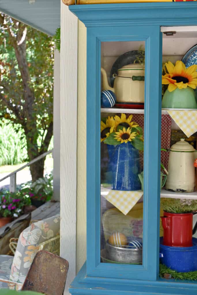 Colorful vintage enamelware displayed in aqua painted cabinet.