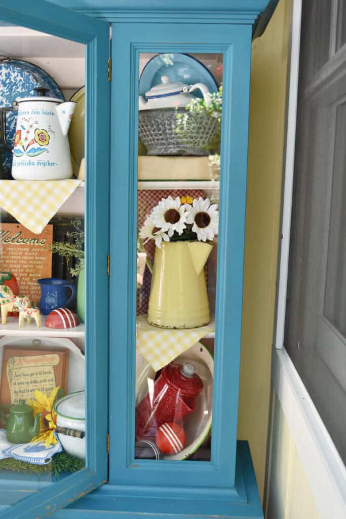 Colorful vintage enamelware displayed in aqua painted cabinet.