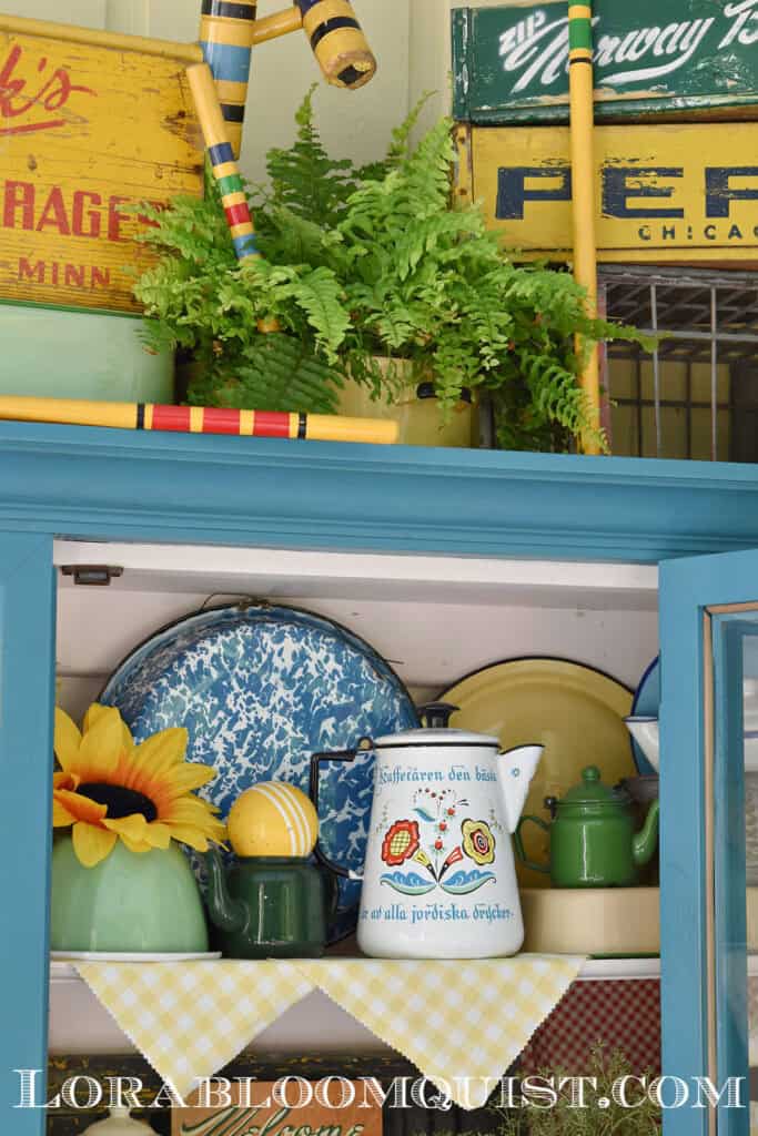 Aqua painted hutch on porch with colorful summer time vintage display.
