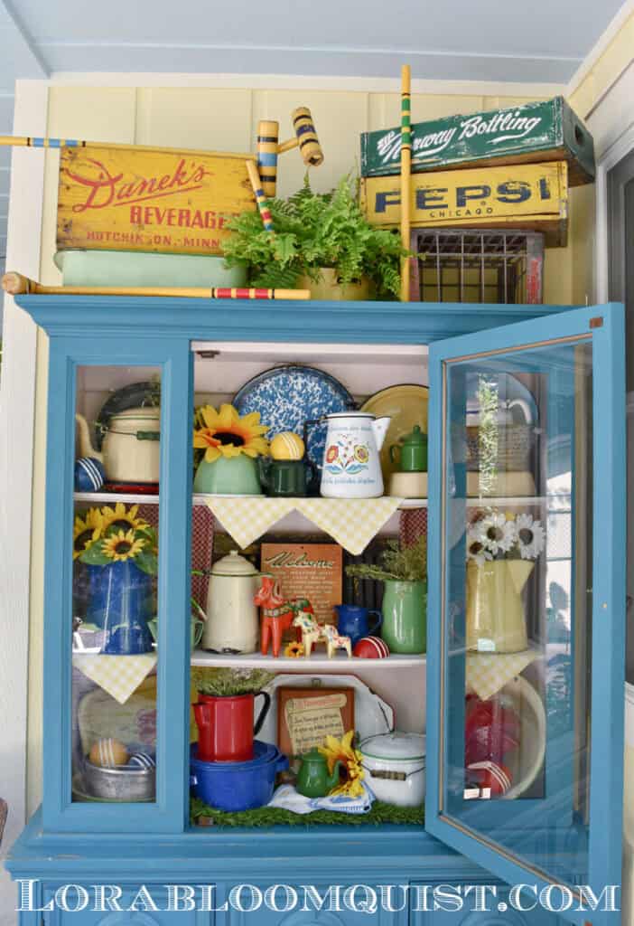Aqua painted hutch on porch with colorful summer time vintage display.
