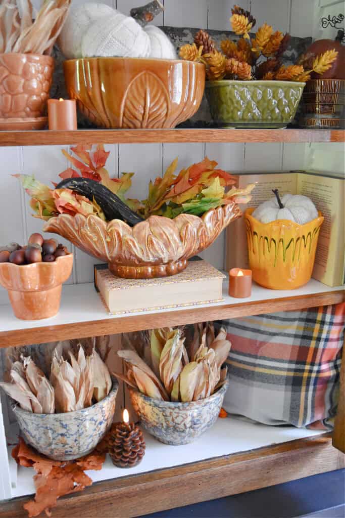 Fall colored vintage pottery display on shelf.