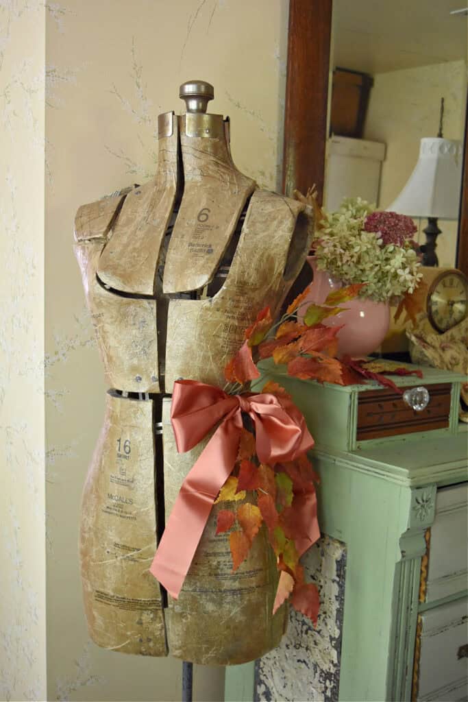Vintage dress form decorated for Fall by green dresser.