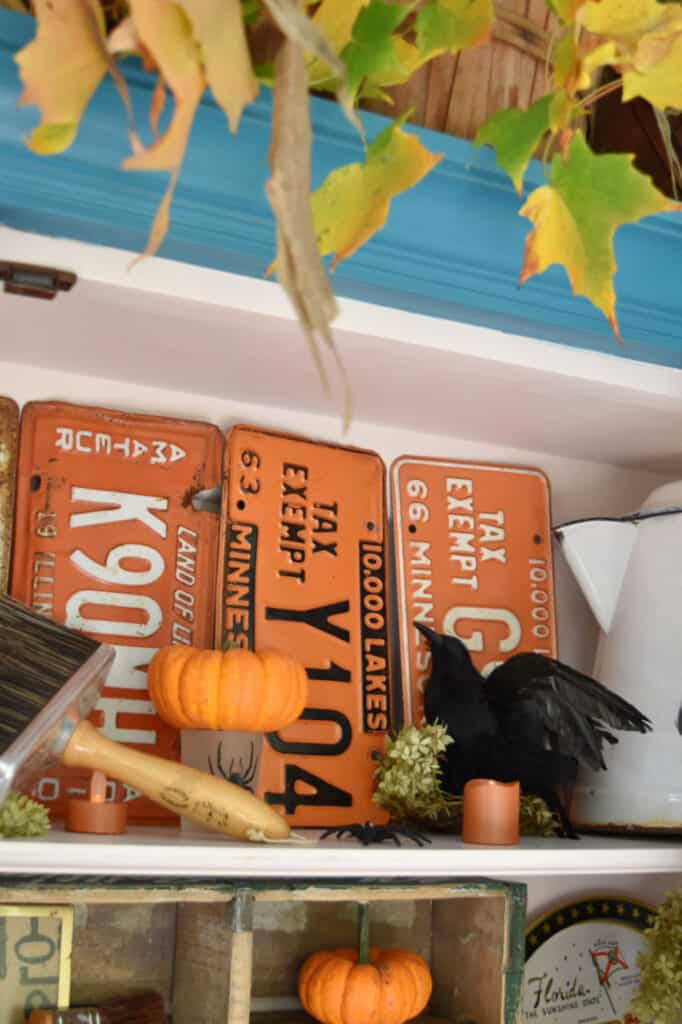 Old orange license plates as Fall porch decor.