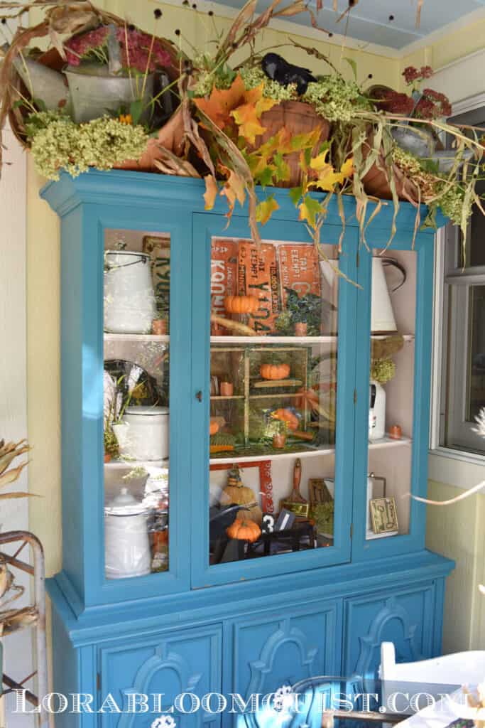 Blue cupboard on porch with Fall decorations.