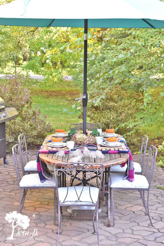 Vintage patchwork quilts and restaurant ware set the table on this Fall decorated porch and patio.