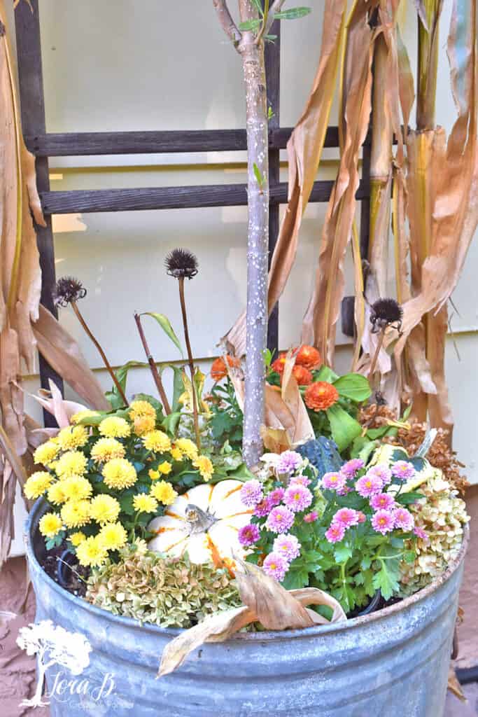 Repurposed metal trash can as outdoor planter on a fall decorated porch and patio tour with salvaged style.