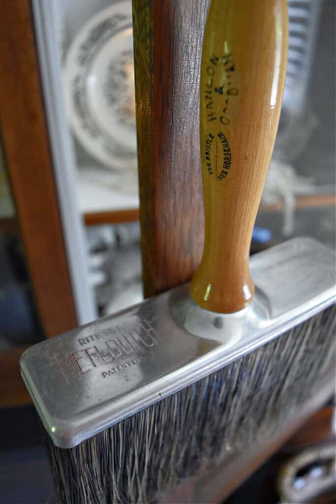Vintage brush hanging on bookshelf.