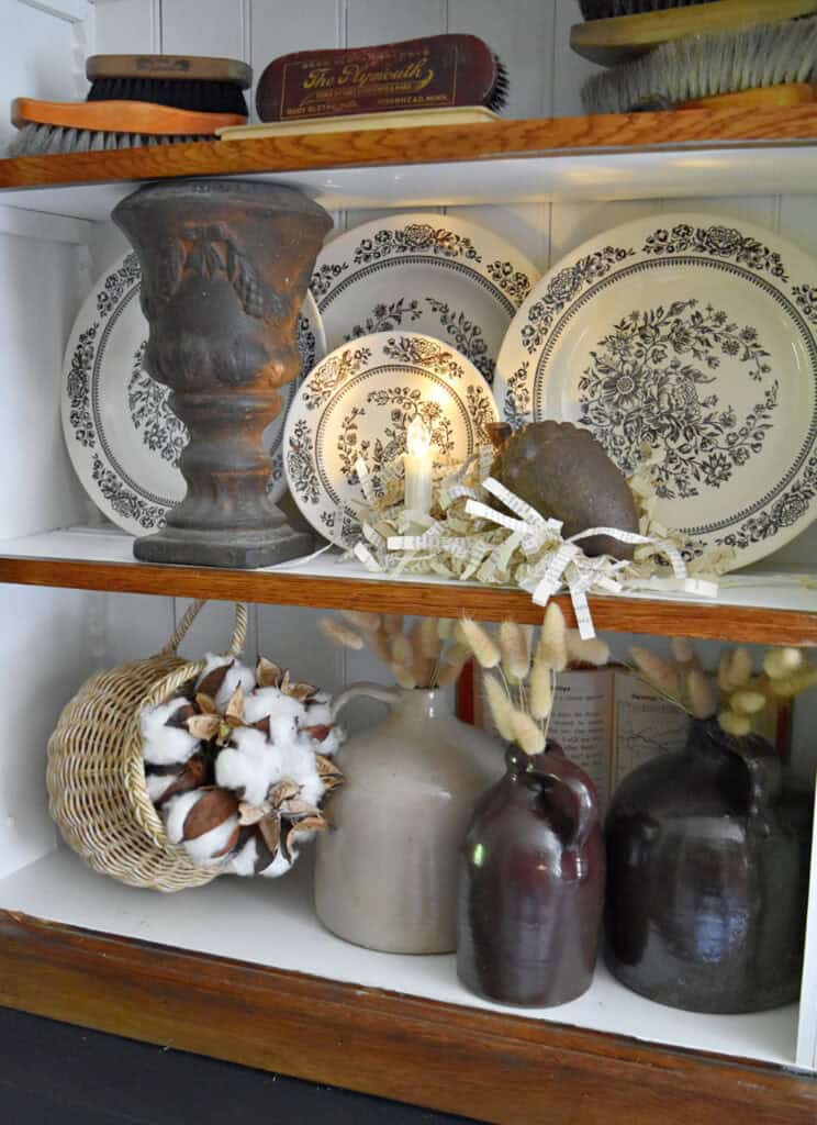 Brown transferware, old brushes, crocks and natural touches in a fall bookshelf display.