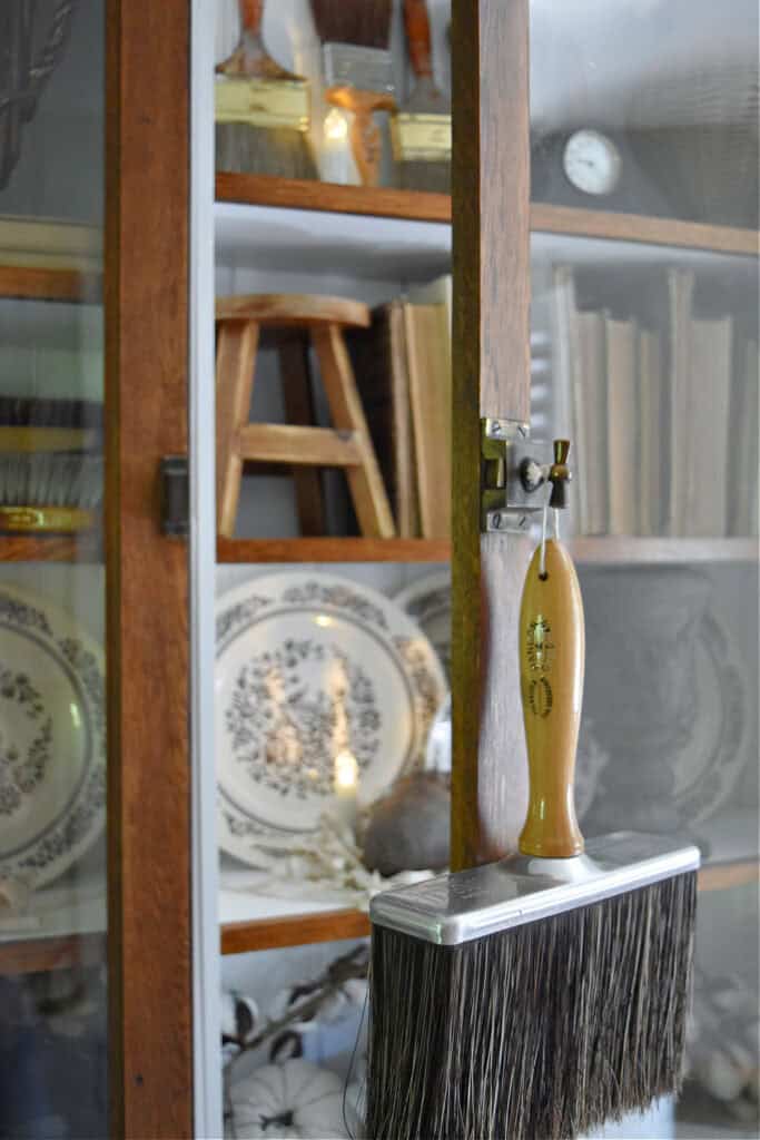 Vintage paintbrush hanging on bookshelf knob.