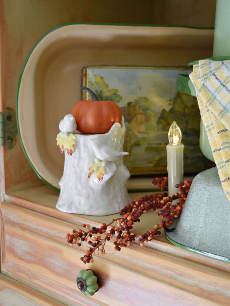 Mini pumpkin on bird figurine in hutch display.