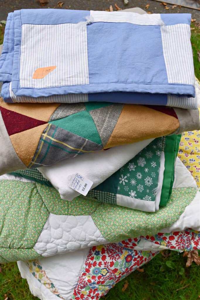 Stack of thrifted patchwork quilts.