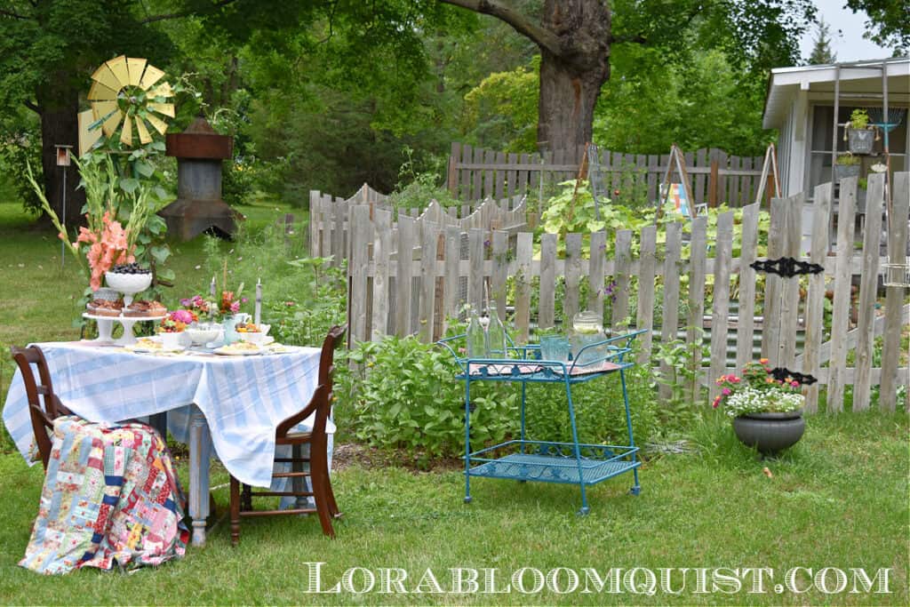 Summer garden party table setting by picket fence.