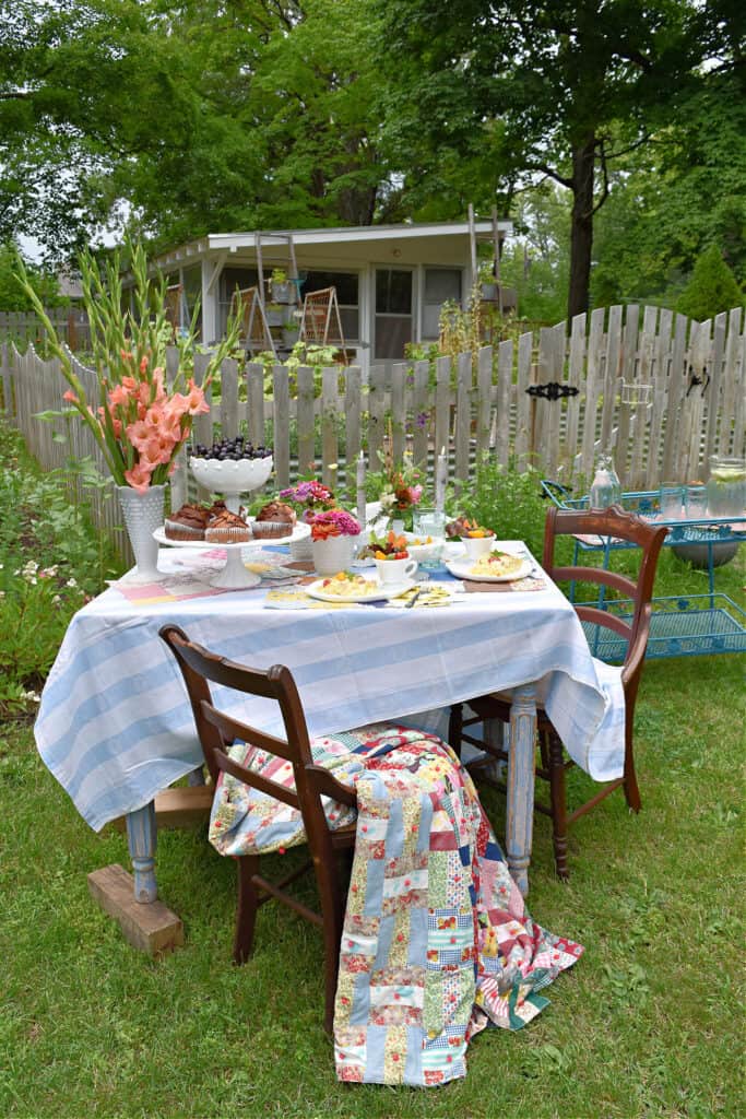 Summer garden party table setting by picket fence.