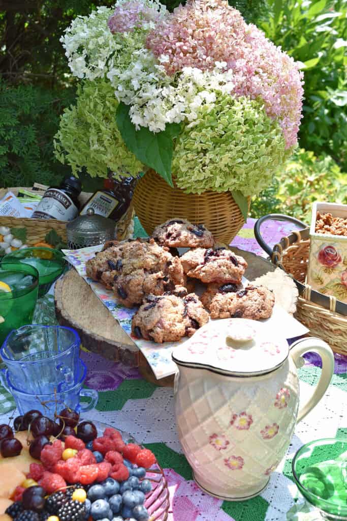Hydrangeas in wicker vase, scones and vintage dishes for a garden party table.