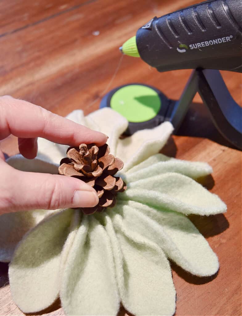 Gluing pinecone onto DIY fabric ornament.