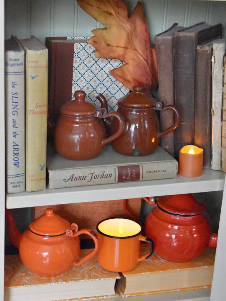 Orange and brown vintage enamelware teapots on display.