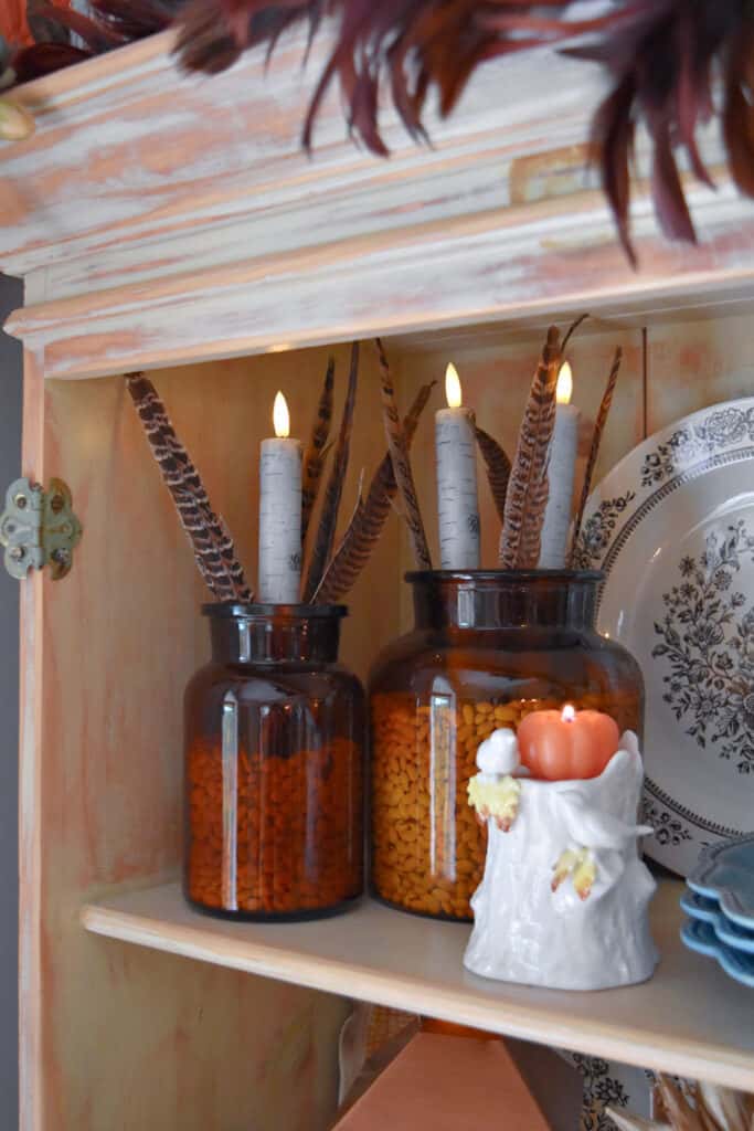 Amber glass vases with feathers and faux candles.