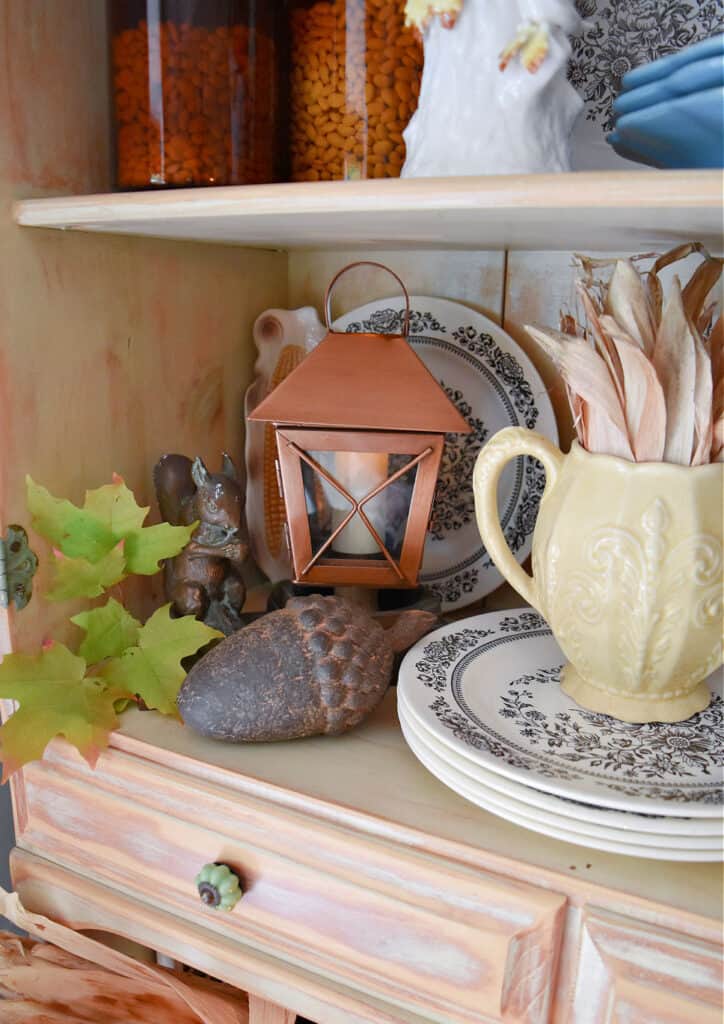 Copper lantern and vintage finds in Fall decorated hutch.