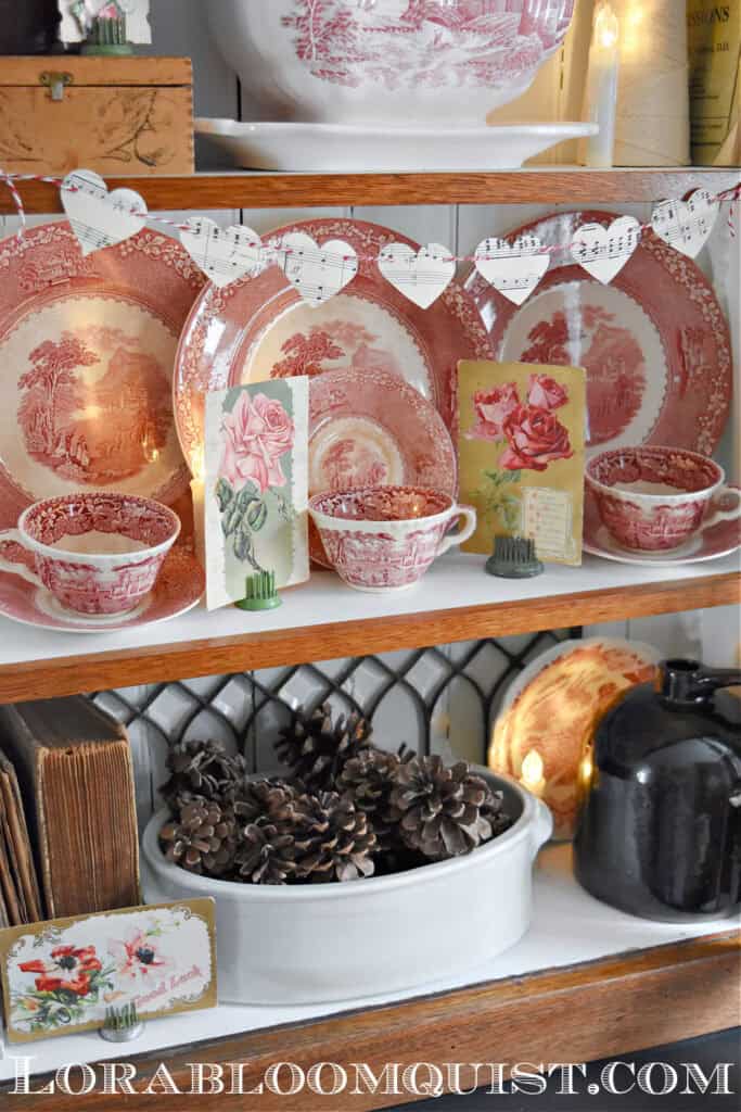 Vintage Valentines Decorations in glass front antique bookshelf with DIY paper heart garland,