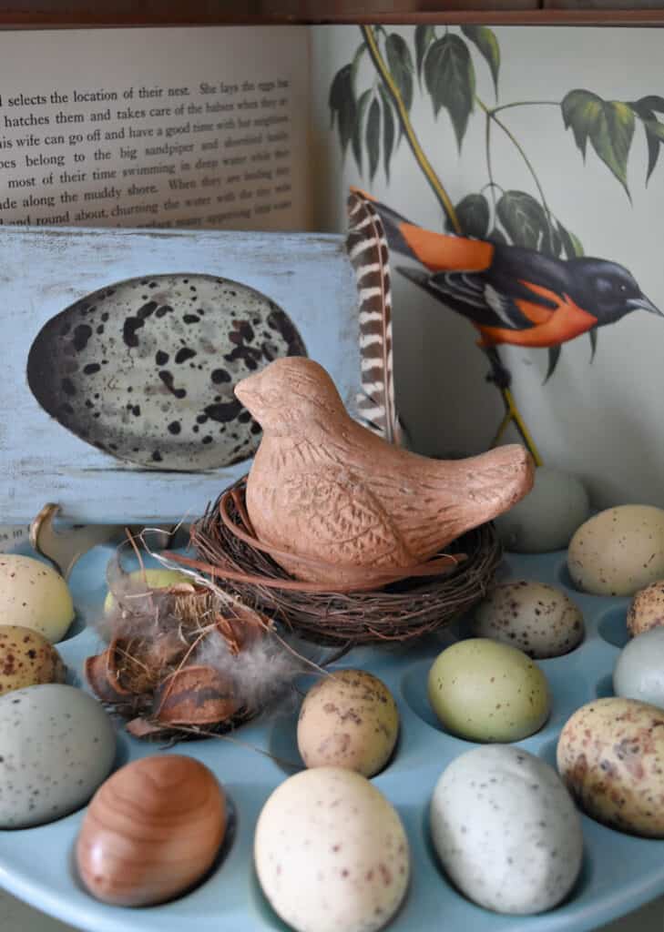 Moss bird and speckled eggs on cake plate as decor.