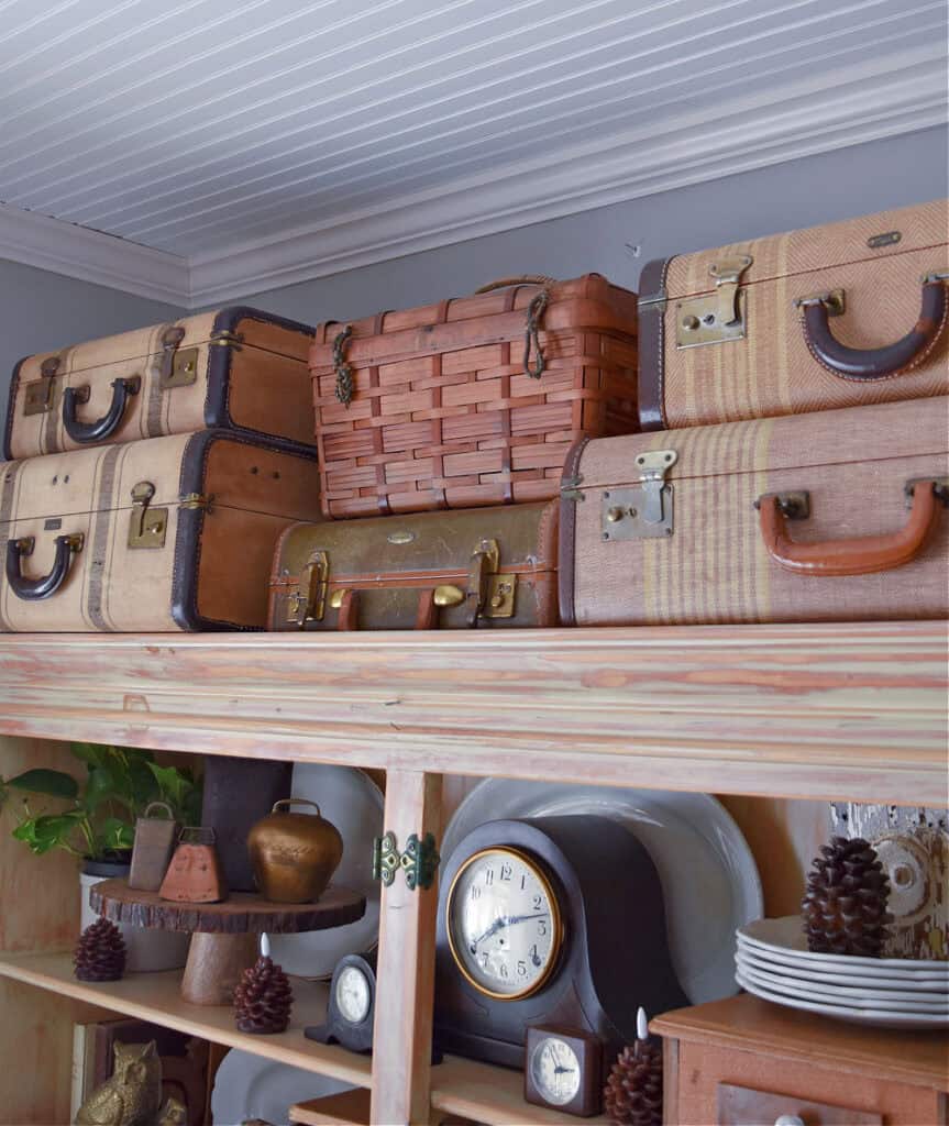 Vintage suitcases and wicker basket on top of hutch.