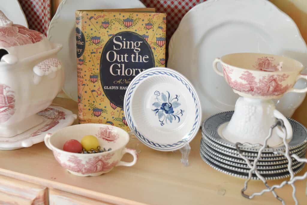 Vintage Americana book in Patriotic hutch display with red, white and blue dishes.