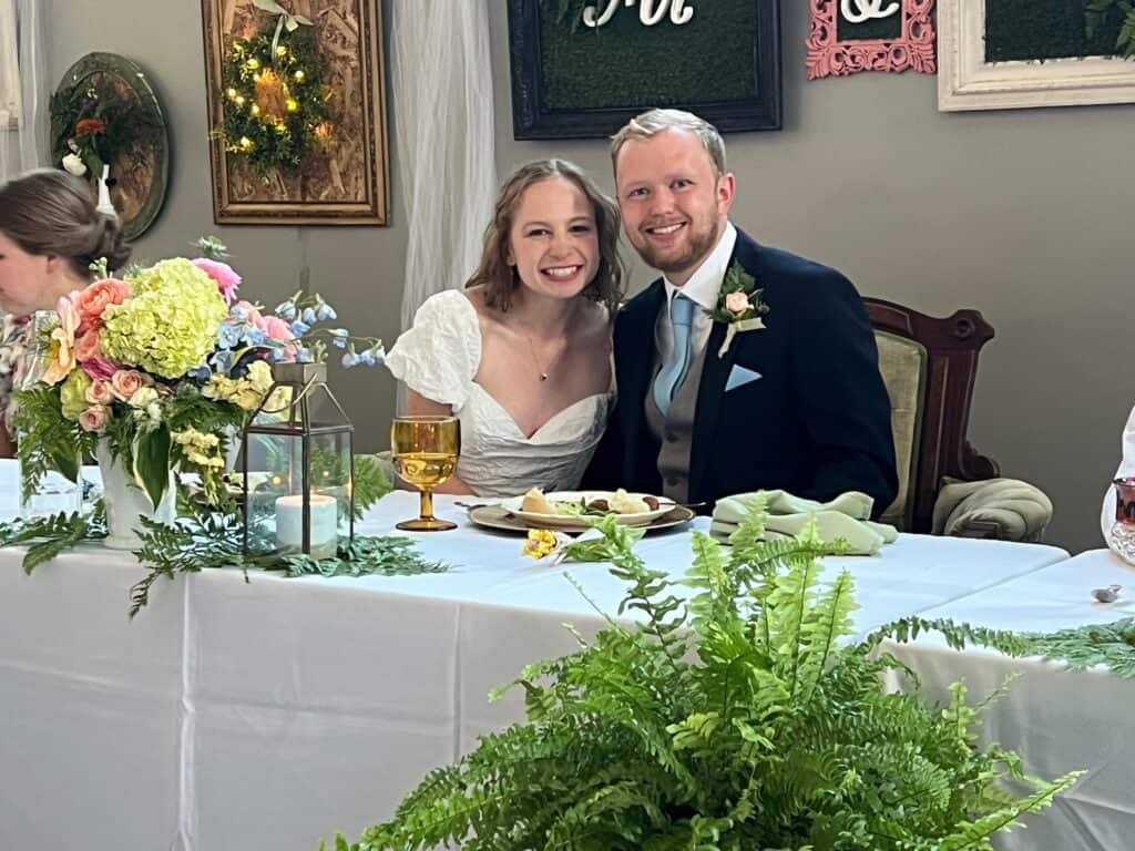 Happy bride and groom sitting at head table.