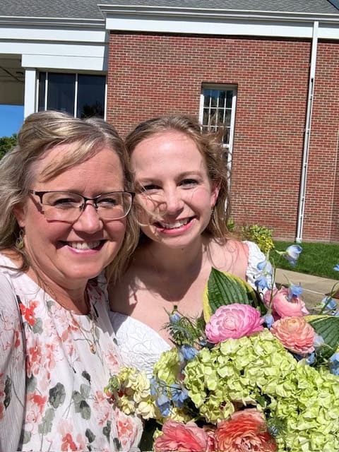 Mom and daughter smiling for wedding photo.